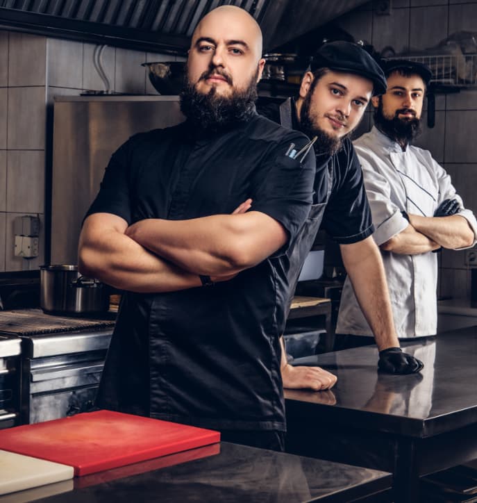 Three chefs standing confidently in kitchen.