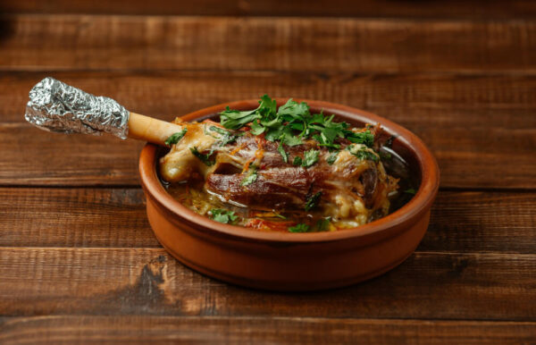 Lamb shank in clay pot with herbs.
