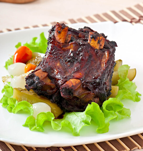 Grilled ribs on lettuce with vegetables.
