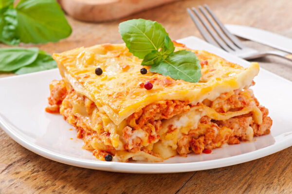 Lasagna slice garnished with fresh basil leaves.