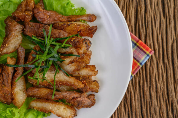 Grilled meat on plate with lettuce garnish.