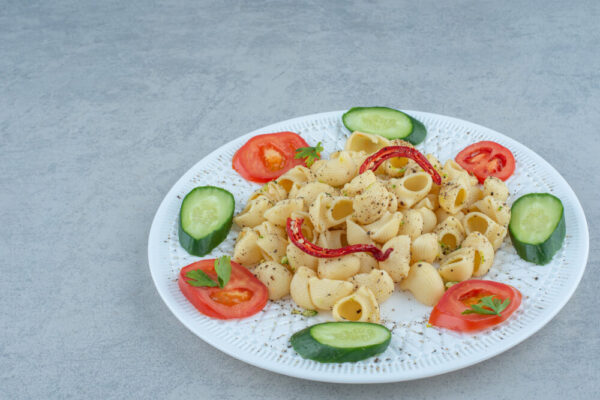 Pasta salad with sliced cucumbers and tomatoes.