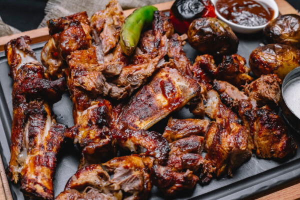 Grilled meat platter with vegetables and sauce.