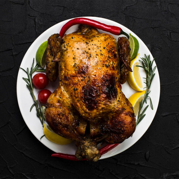Roast chicken with garnish on white plate.