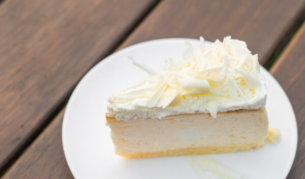 Slice of cheesecake with white chocolate topping.