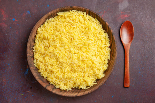 Bowl of yellow rice with wooden spoon.