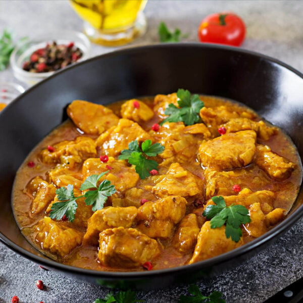 Spicy chicken curry in black bowl.