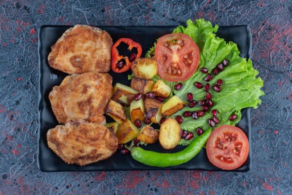 Fried chicken, potatoes, and vegetables on plate.